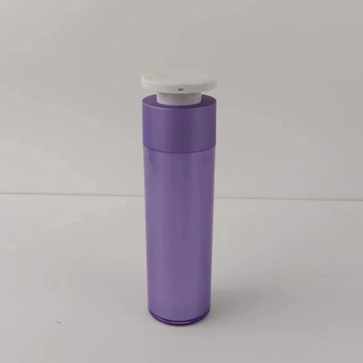 Paarse plastic cosmetische dispenserfles met witte drukknop pomp